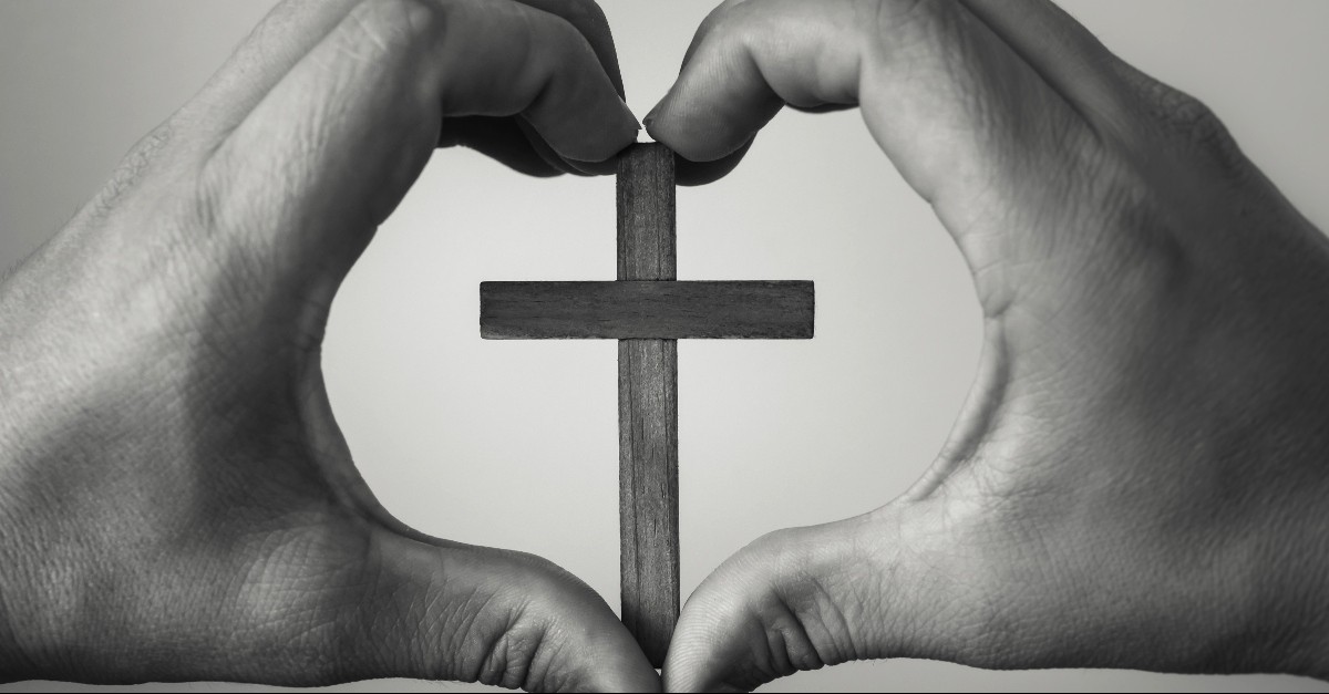 Heart hands over a cross
