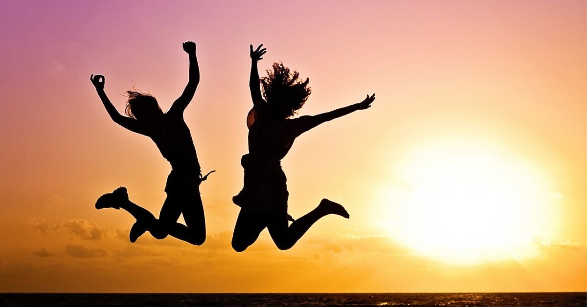 Friends Jumping By a Lake at Sunset; Easter promises community.